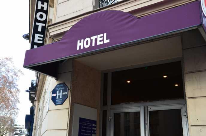 Entrée d'hôtel avec un auvent violet affichant le mot HOTEL en lettres blanches.